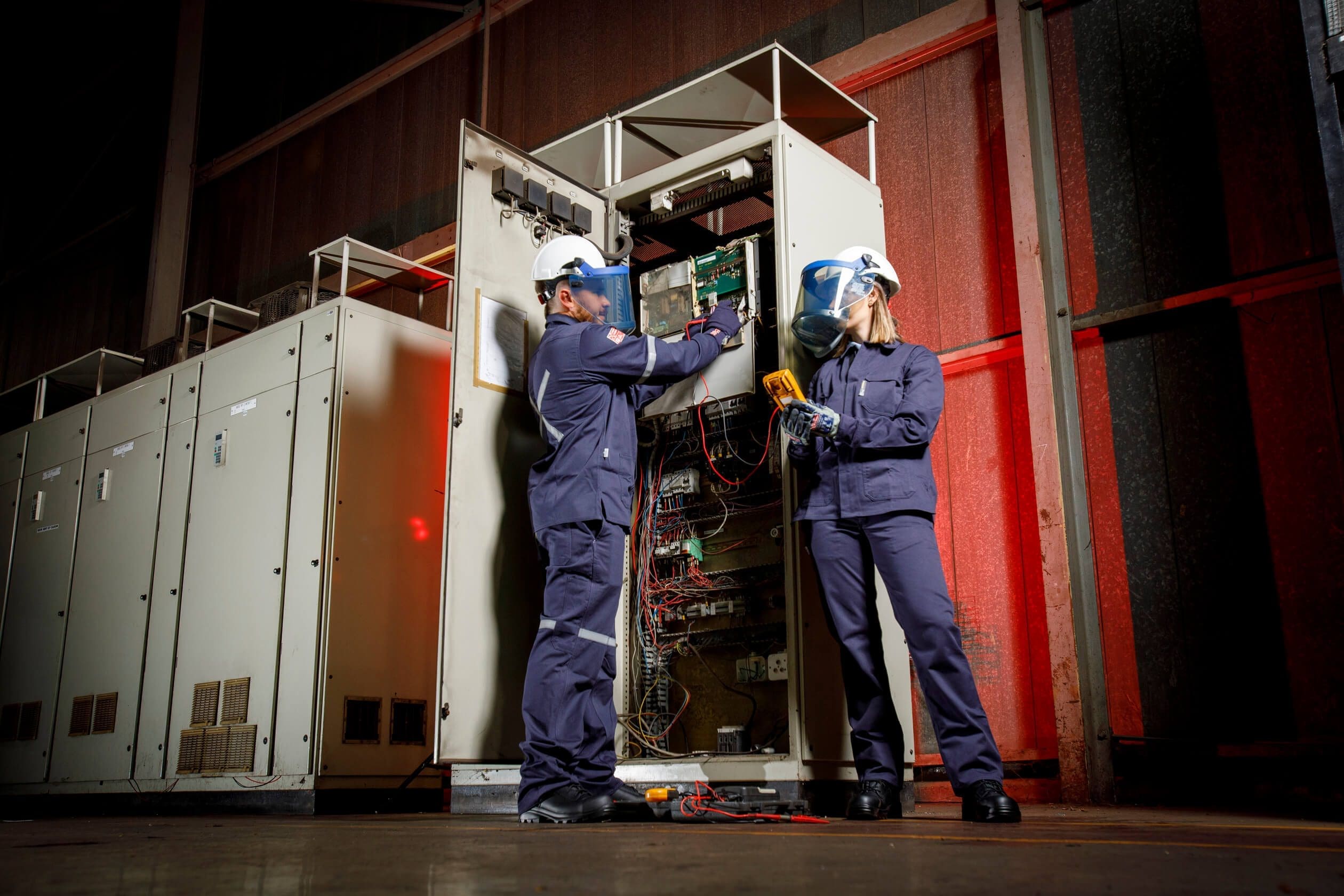 a man and woman wearing helmets and working on a machine